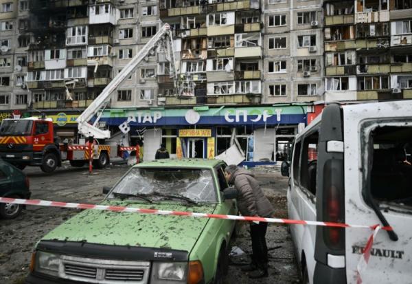 Un habitant inspecte une voiture endommagée devant un immeuble résidentiel touché à la suite d’une attaque aérienne à Kiev, le 29 novembre 2025