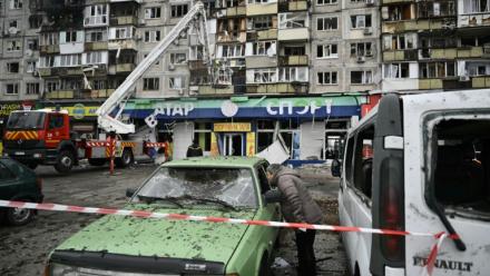 Un habitant inspecte une voiture endommagée devant un immeuble résidentiel touché à la suite d’une attaque aérienne à Kiev, le 29 novembre 2025