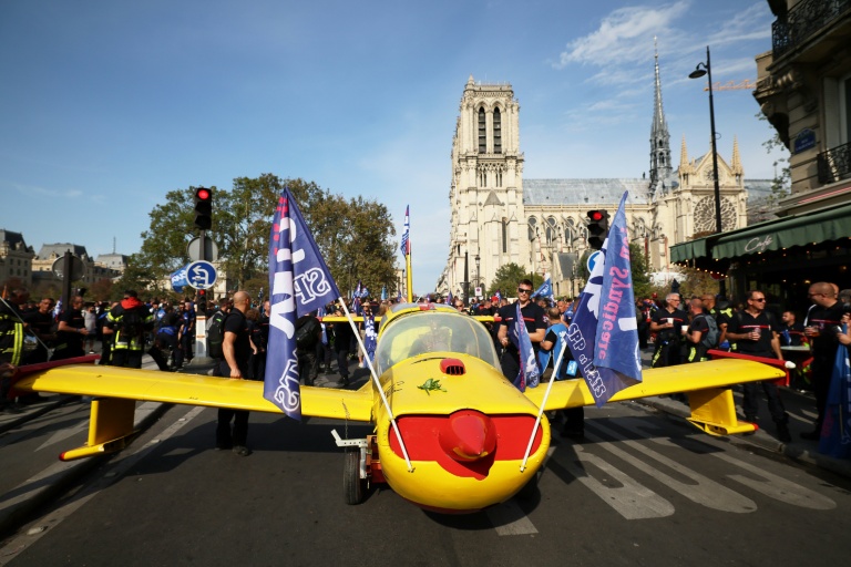 Des pompiers installent un avion peint aux couleurs de la Sécurité civile devant la cathédrale Notre-Dame de Paris, lors d'une manifestation pour réclamer des hausses de salaires et des moyens budgétaires accrus, le 28 septembre 2026 à Paris