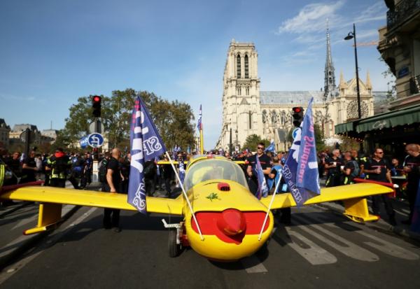 Des pompiers installent un avion peint aux couleurs de la Sécurité civile devant la cathédrale Notre-Dame de Paris, lors d'une manifestation pour réclamer des hausses de salaires et des moyens budgétaires accrus, le 28 septembre 2026 à Paris