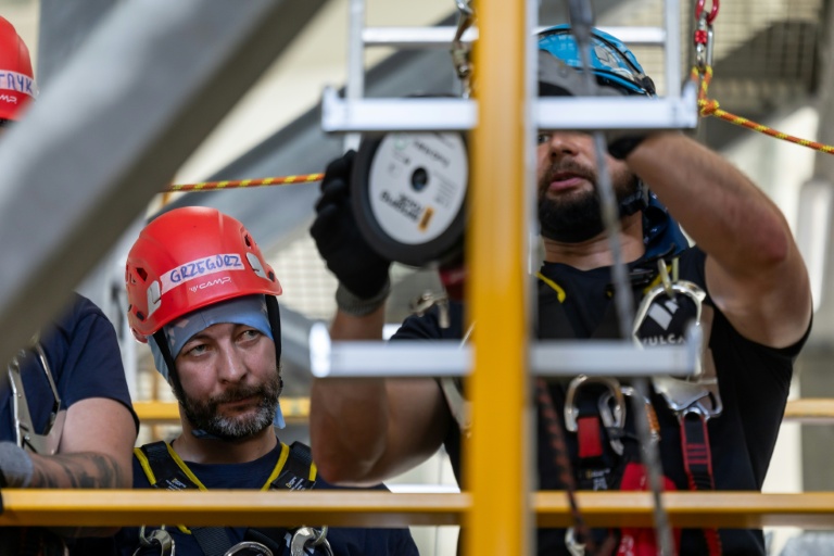 Le mineur Grzegorz Witek (g), participant au programme de formation pour techniciens d'éoliennes, lors d'un stage sur la sécurité, le sauvetage et l'évacuation en hauteur au centre de formation Vulcan à Szczecin, dans le nord-ouest de la Pologne, le 23 juin 2026
