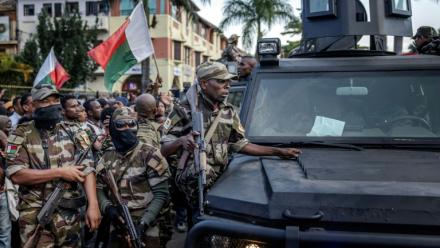 Des soldats malgaches en véhicules blindés sont entourés de manifestants saluant leur arrivée à l'hôtel de ville d'Antananarivo, le 11 octobre 2025