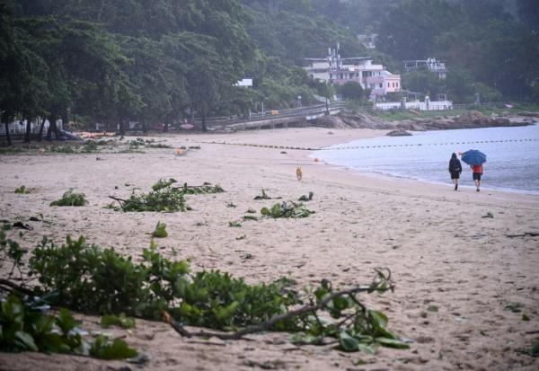 Des personnes se promènent sur une plage jonchée de débris laissés par le typhon Noul, à Hong Kong, le 26 juillet 2026
