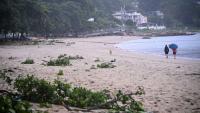 Des personnes se promènent sur une plage jonchée de débris laissés par le typhon Noul, à Hong Kong, le 26 juillet 2026