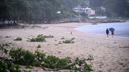 Des personnes se promènent sur une plage jonchée de débris laissés par le typhon Noul, à Hong Kong, le 26 juillet 2026