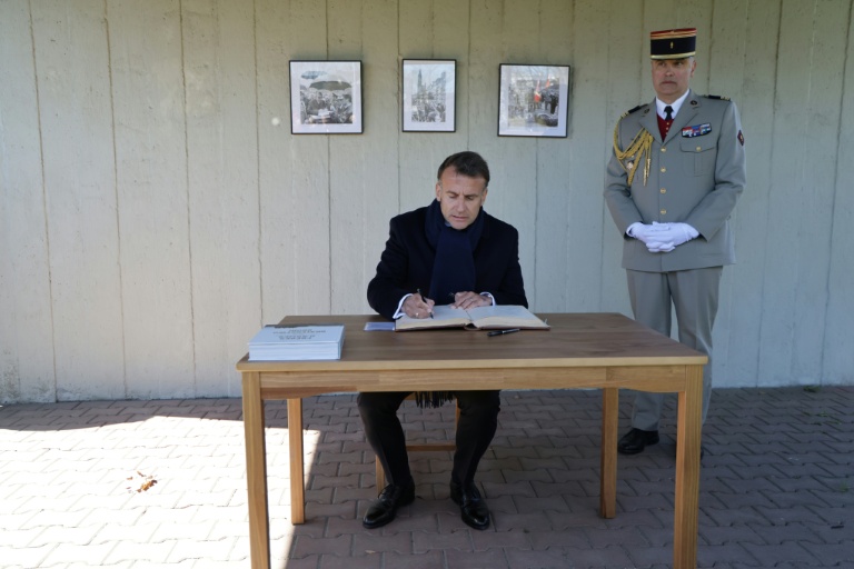Le président français Emmanuel Macron (g) signe le livre d'or au cimetière militaire français, tandis qu'en arrière-plan apparaissent des photos de la visite officielle du président français Charles de Gaulle en 1967, le 20 avril 2026 à Gdansk, en Pologne