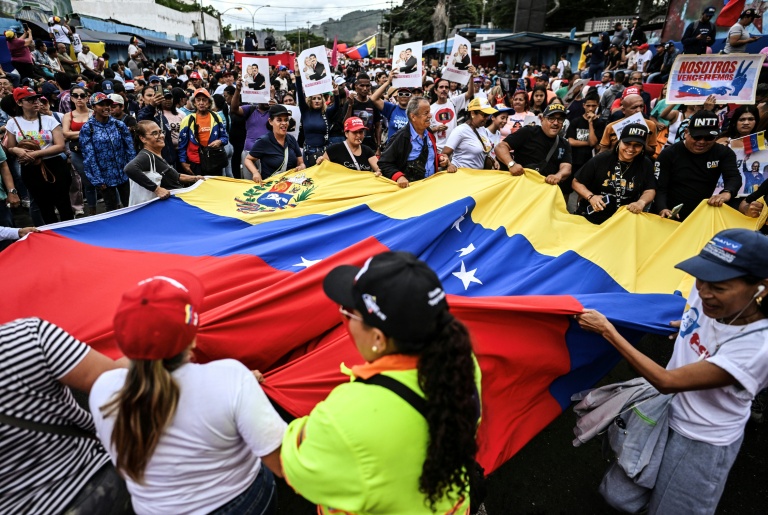 Des manifestants brandissent un drapeau vénézuélien géant lors d'un rassemblement en soutien au président vénézuélien déchu Nicolas Maduro à Caracas, le 10 janvier 2026