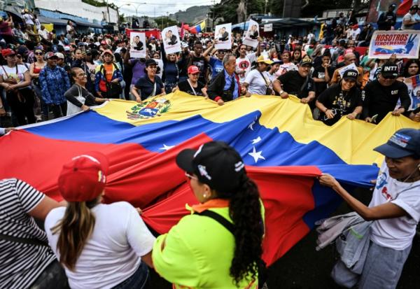 Des manifestants brandissent un drapeau vénézuélien géant lors d'un rassemblement en soutien au président vénézuélien déchu Nicolas Maduro à Caracas, le 10 janvier 2026