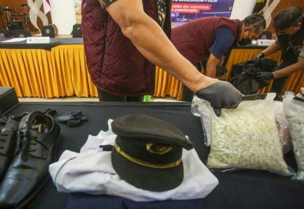Des agents des douanes présentent l'uniforme d'un pilote ainsi que la drogue qu'il a fait passer en contrebande, lors d'une conférence de presse à l'aéroport international Soekarno-Hatta de Tangerang, près de Jakarta, le 31 juillet 2026 en Indonésie