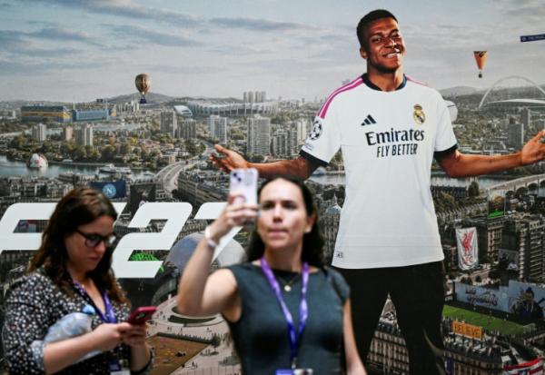 Une joueuse prend un selfie devant une publicité du jeu EA SPORTS FC 27 représentant la star française Kylian Mbappé, au salon Gamescom, à Cologne le 26 août 2026