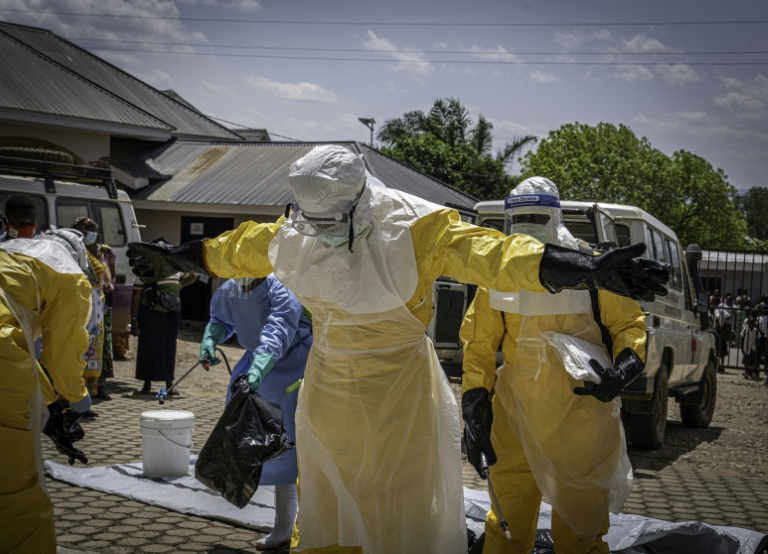Des agents de santé sont aspergés de désinfectant après avoir été en contact avec le corps d'une personnes suspectée d'être morte de la maladie d'Ebola à Bunia, dans l'est de la République démocratique du Congo, le 25 mai 2026