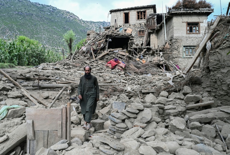 Un homme afghan passe devant une maison endommagée à la suite de tremblements de terre dans le village de Mazar Dara, situé dans le district de Nurgal, dans la province de Kunar, à l'est de l'Afghanistan, le 1er septembre 2025 après un séisme de magnitude 6,0