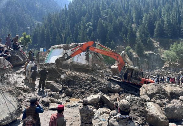 Un engin de chantier déblaient les décombres de boutiques détruites par des crues soudaines à Parun, dans la province du Nouristan, le 21 juillet 2026 en Afghanistan