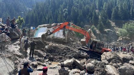 Un engin de chantier déblaient les décombres de boutiques détruites par des crues soudaines à Parun, dans la province du Nouristan, le 21 juillet 2026 en Afghanistan
