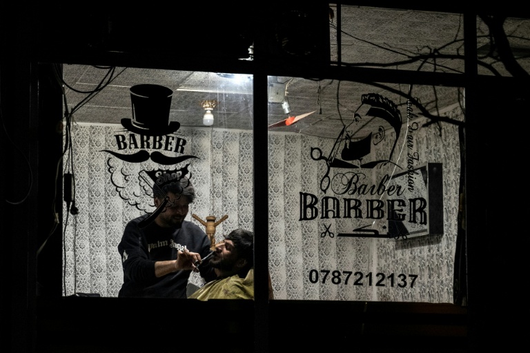 Un barbier taille la barbe d'un client dans un salon à Kaboul le 11 février 2026