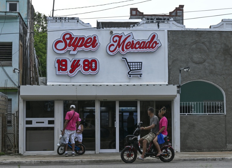Des passants discutent devant une épicerie privée à La Havane, le 22 juin 206