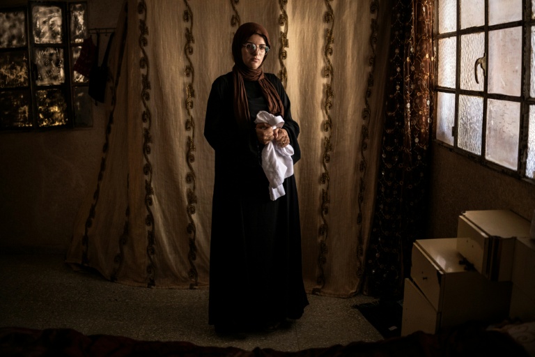 Alia al-Hallaq, la mère de Mohammed, tué à 9 ans par un soldat israélien en octobre 2025, tient le thobe de son fils, dans le village d'al-Rihiya, en Cisjordanie occupée, le 16 juillet 2026