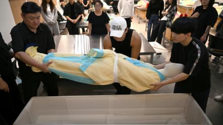 Des étudiants s'entraînent sur un mannequin au rite de  la mise en bière dans une salle de classe de l'Institut des sciences et technologies de Busan, dans le sud-est de la Corée du Sud, le 24 septembre 2025