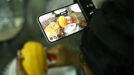 Nagireddy Sriramyachandra filme avec un téléphone ses gestes pendant qu'elle coupe une mangue pour entraîner un futur robot dopé à l'IA, le 15 mai 2026 à Madras, en Inde