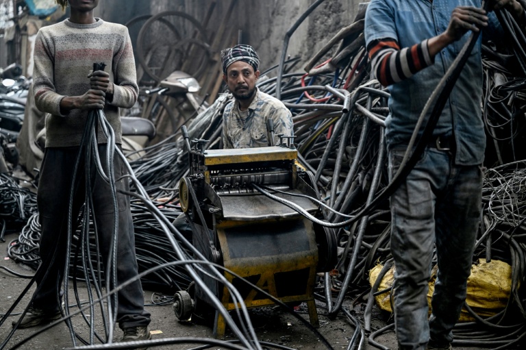 Des hommes récupérant de l'aluminium de fils plastiques dans un centre informel de recyclage de Seelampur, à New Delhi en Inde, le 28 janvier 2026