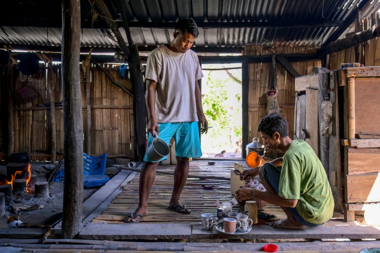 Le noble Umbu Ana Rara (g) regarde son esclave (d) Kanisius Kanyali Hambarita préparer des boissons au village de Tanggedu, dans l'est de l'île de Sumba, le 23 juin 2026 en Indonésie