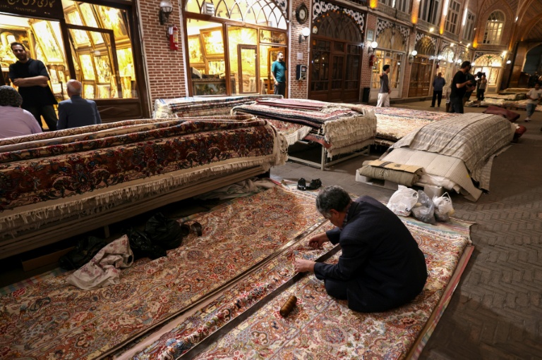 Un artisan travaille sur un tapis persan au marché de Tabriz, dans le nord-ouest de l'Iran, le 17 septembre 2025
