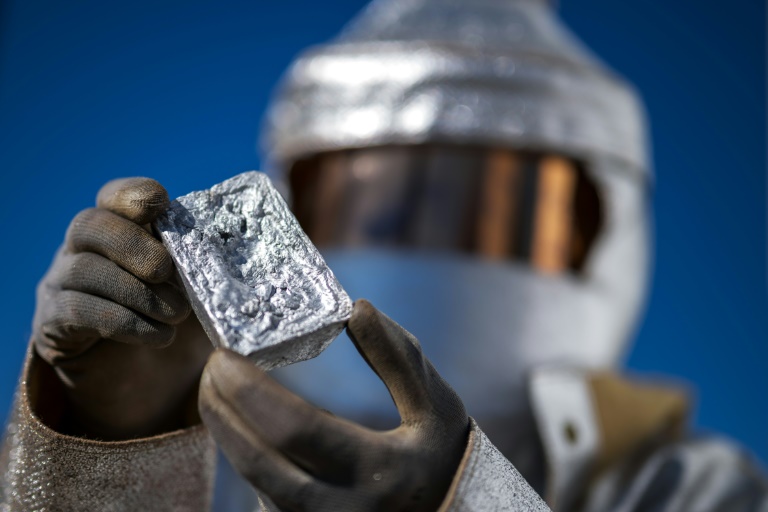 Un ingénieur métallurgique en tenue de protection montre un lingot d'aluminium durant la présentation d'un four solaire de l'entreprise Panatère à La Chaux-de-Fonds, en Suisse, le 2 octobre 2025 