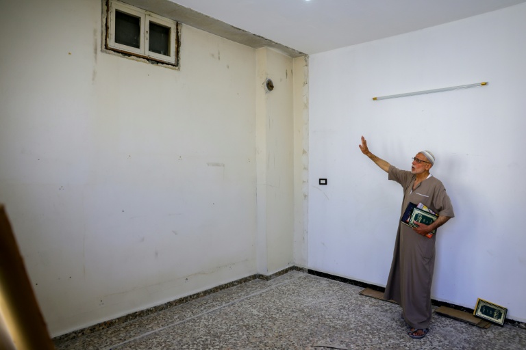 Mustafa Khaled Alwan montre l'emplacement du faux mur qui dissimulait sa bibliothèque, chez lui à Homs, en Syrie, le 19 septembre 2026