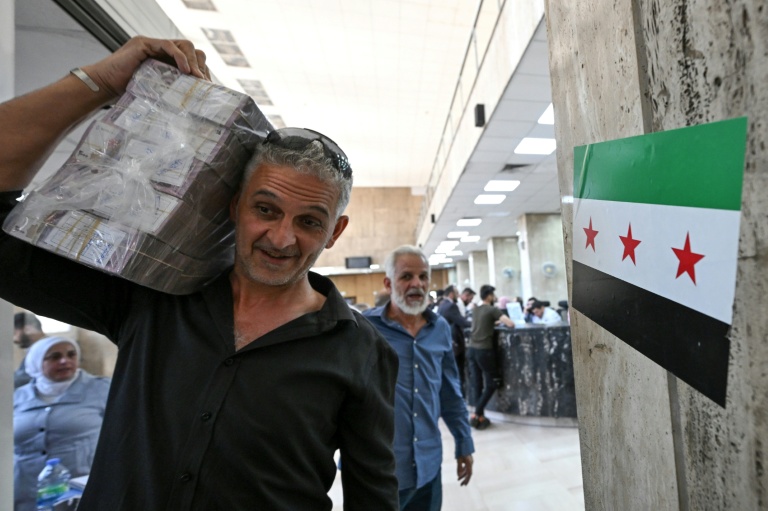 Un homme quitte la banque centrale de Damas avec des livres syriennes, le 21 mai 2025