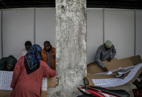 Des électeurs cherchent leur nom sur la liste électorale dans un bureau de vote de Stone Town (Tanzanie), le 29 octobre 2025