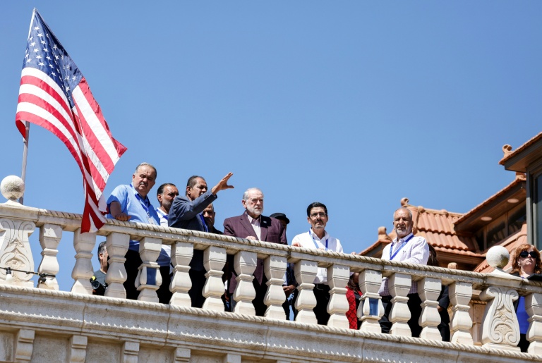 L'ambassadeur des États-Unis en Israël, Mike Huckabee (c), sur le toit de la maison d'un résident palestino-américain, harcelé par des colons israéliens, observe la colonie juive érigée près de la ville de Turmus Ayya, en Cisjordanie, le 5 septembre 2026