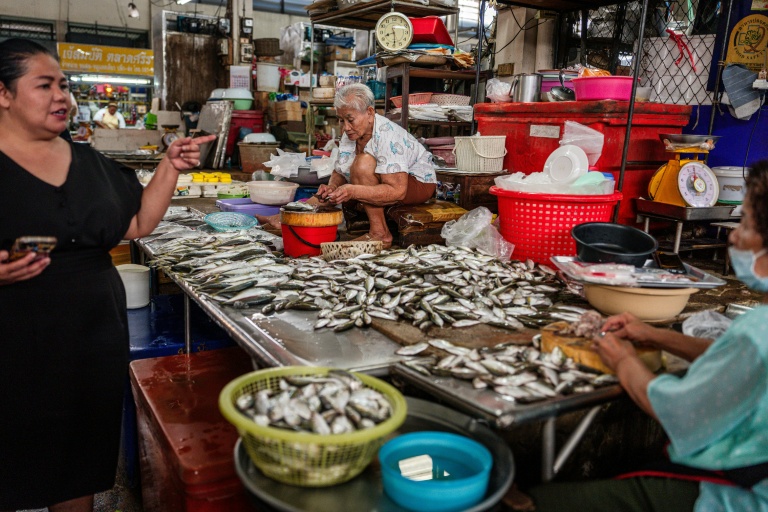 Le vendeur de poisson Sopa Chaiyakul (C) prépare du poisson pour la vente sur un marché de produits frais à Si Racha le 18 mars 2026 en Thaïlande