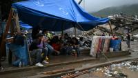 Des rescapés du double séisme s’abritent sous une bâche tandis que les secouristes fouillent les décombres des immeubles effondrés à Caraballeda, dans l’État de La Guaira, au Venezuela, le 11 juillet 2026