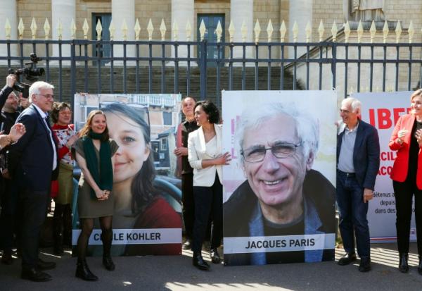 Cécile Kohler (3e G) et Jacques Paris (2e D) devant leurs portraits décrochés des grilles de l'Assemblée nationale, à Paris le 14 avril 2026