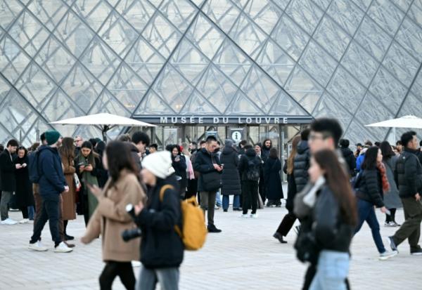 Des visiteurs devant la pyramide du Louvre le 15 décembre 2025 à Paris