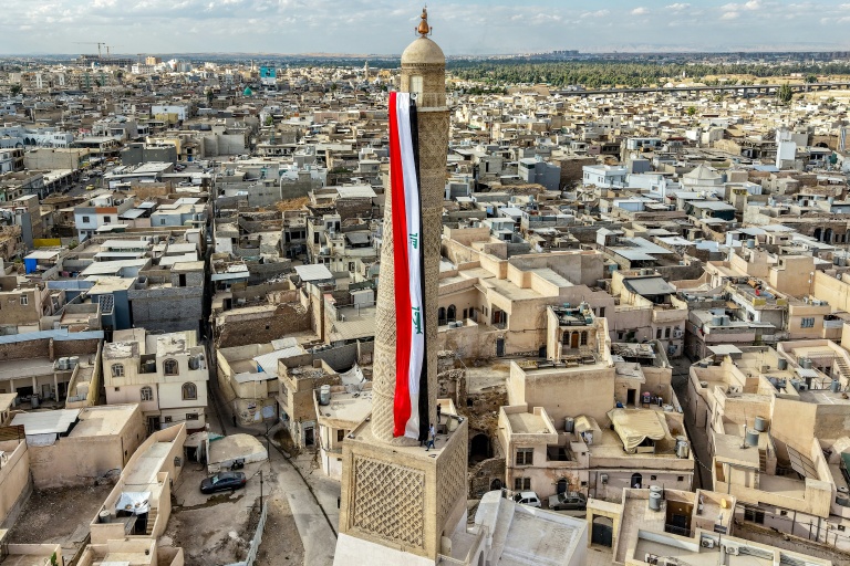 Un drapeau irakien géant est suspendu au minaret penché Hadba, datant du XIIᵉ siècle et reconstruit, dans la vieille ville de Mossoul, le 29 septembre 2026