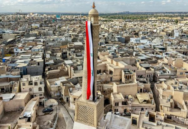 Un drapeau irakien géant est suspendu au minaret penché Hadba, datant du XIIᵉ siècle et reconstruit, dans la vieille ville de Mossoul, le 29 septembre 2026