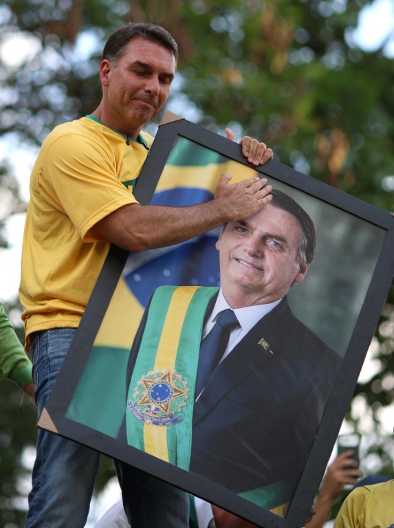Le candidat à la présidentielle brésilienne Flavio Bolsonaro tient un portrait de son père, l'ex-président Jair Bolsonaro, devant ses soutiens à Goiania, au Brésil, le 27 septembre 2026