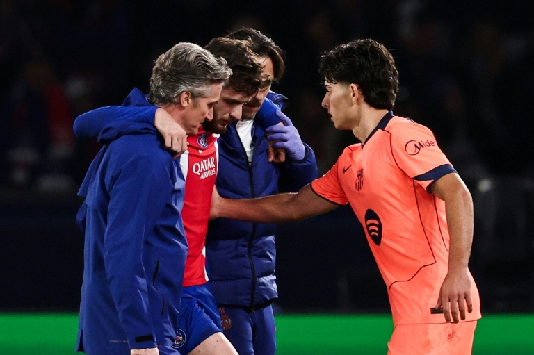 L'attaquant du PSG Khvicha Kvaratskhelia (c) quitte la pelouse après s'être blessé au genou droit lors du match contre le FC Barcelone, réconforté par Xavi Espart, le 20 octobre 2026 au Parc des Princes