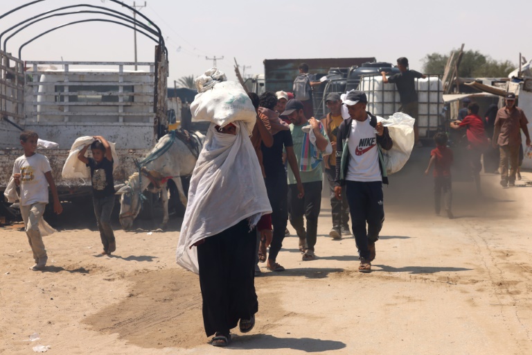 Des Palestiniens transportent de l'aide humanitaire dans le quartier de Mawasi à Rafah, dans le sud de la bande de Gaza, le 18 août 2025