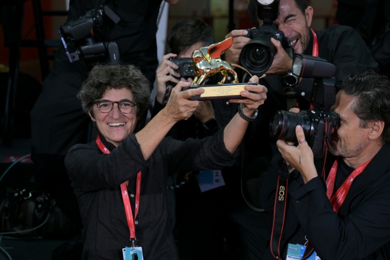 La photojournaliste de l'AFP Tiziana Fabi (g) brandit le Lion d'or remis à l'acteur et réalisateur George Clooney à Venise, le 2 septembre 2026 