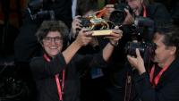 La photojournaliste de l'AFP Tiziana Fabi (g) brandit le Lion d'or remis à l'acteur et réalisateur George Clooney à Venise, le 2 septembre 2026 