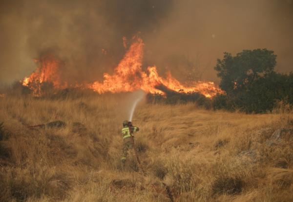 Un pompier tente d'éteindre un feu qui fait rage dans la région de Megara, au nord-ouest d'Athènes, le 3 août 2026.
