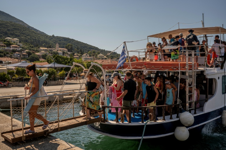 Des touristes débarquent d'un bateau après être revenus des plages voisines de l'île grecque d'Ithaque, dans la mer Ionienne, le 3 août 2026