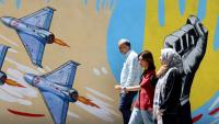 Des Iraniens passent devant des graffitis anti-américains et anti-israéliens, à Téhéran le 10 mai 2026
