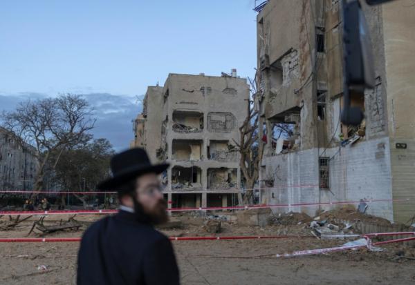 Un juif orthodoxe israélien regarde le site d'une frappe de missile iranien à Arad, dans le sud d'Israël, le 22 mars 2026