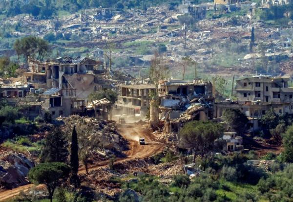 Un véhicule militaire israélien passe devant des maisons détruites par des frappes israéliennes dans le sud du Liban, vu depuis une position de l’autre côté de la frontière, en Haute Galilée, au nord d’Israël, le 7 mai 2026