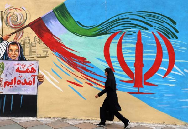 Une femme passe devant une fresque murale anti-américaine et et anti-israélienne à Téhéran, le 21 avril 2026