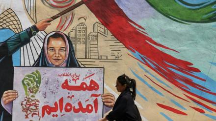 Une Iranienne passe devant une fresque anti-américaine et anti-israélienne sur laquelle on peut lire "Pour la révolution, nous sommes tous venus", dans la capitale Téhéran, le 10 mai 2026