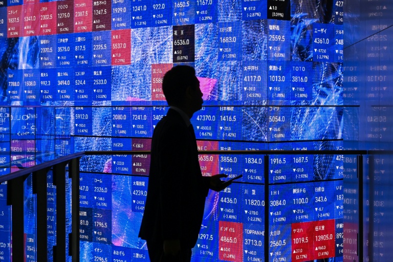 Une personne attend devant un panneau électronique à la Bourse de Tokyo, le 5 novembre 2025